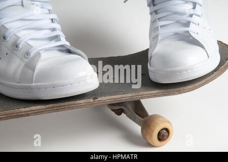 Personne tient la planche à roulettes avec pieds à part sur un vieux skateboard Banque D'Images