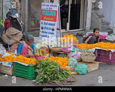 Guirlande de fleurs non identifiées et légumes vendeur dans une rue d'Ahmedabad. Les guirlandes, utilisé à des fins religieuses et rituelles, sont réalisées en situ Banque D'Images