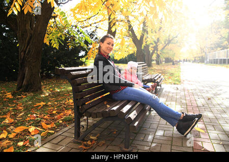 Les jeunes femmes et sa fille assis sur un banc dans le parc Banque D'Images