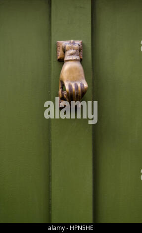 Heurtoir laiton original dans la forme d'une main, les portes en bois vert, belle décoration Banque D'Images