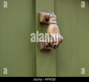 Vue côté gauche sur un heurtoir laiton original dans la forme d'une main, les portes en bois vert, belle décoration Banque D'Images