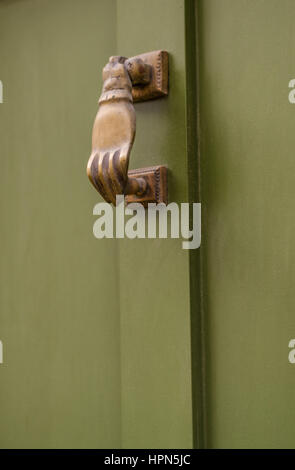 Vue côté droit sur un heurtoir laiton original dans la forme d'une main, les portes en bois vert, belle décoration Banque D'Images