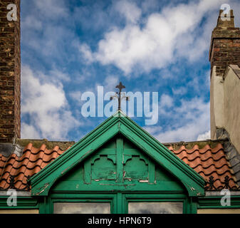 Dormeur en bois peint vert dans un toit en tuiles rouges avec des éléments décoratifs en métal sur le dessus, Thirsk, North Yorkshire, Royaume-Uni. Banque D'Images