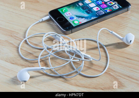 Bangkok, Thaïlande - 22 Février, 2017 : Apple iPhone5s avec écouteurs Earpods fil malpropre sur fond de bois. Banque D'Images