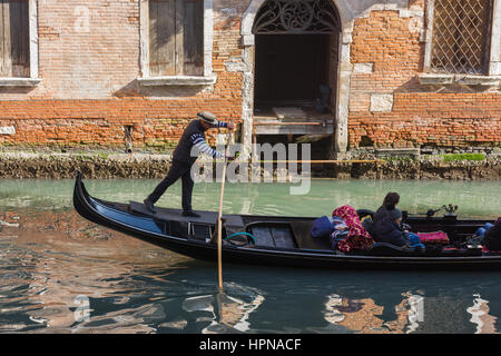 Un Gondolier est vu portant le chapeau de Gondolier traditionnels tandis que l'aviron le long d'un canal interne à Venise, Italie Banque D'Images