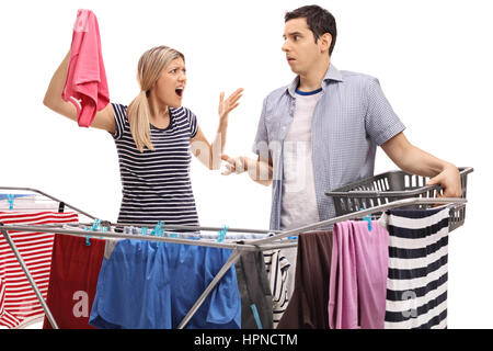 Young couple having an argument tandis que d'étendage sur un rack de vêtements cheveux isolé sur fond blanc Banque D'Images