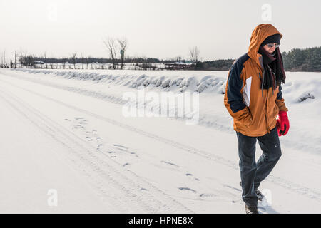 Homme marchant sur la route de campagne tranquille au Canada avec de légères chutes de neige Banque D'Images