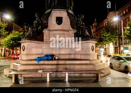 Personne sans-abri dormant sur O'Connell statue dans le centre-ville, Dublin, Irlande Banque D'Images