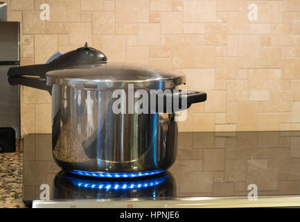 Acier inoxydable autocuiseur se défouler sur une plaque de cuisson à induction modernes avec plateau en verre Banque D'Images