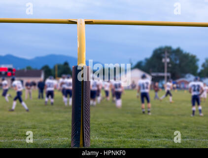 Football américain jaune poteaux de but à l'école avec l'élève sur le terrain les athlètes sur le terrain Banque D'Images