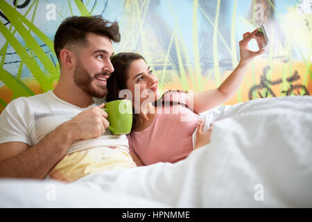 Jeune couple matin au lit selfies Banque D'Images