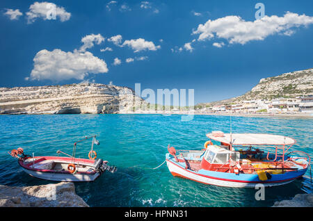 La plage de Matala sur l'île de Crète, Grèce. Il y a deux bateaux dans l'avant-plan et de nombreuses grottes près de la plage. Banque D'Images