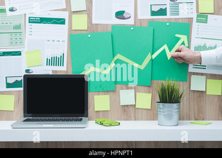 Businessman de la composition d'un tableau financier réussi avec la flèche pointant vers le haut, il est à l'aide de coupes de papier vert, eco business et la réussite financière concept Banque D'Images