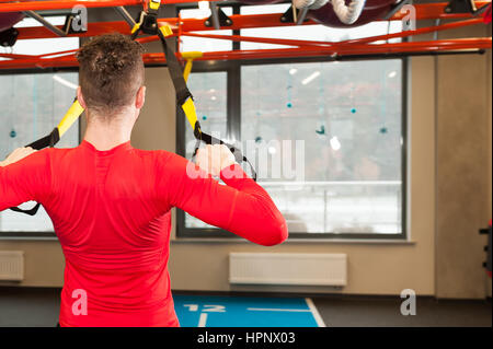 Barbu frisé blanc sporty man exercising with fitness fitness instructeur Crossfit dans sangles au gym faire Excersise. Homme Fitness workout sur les anneaux. Sport et fitness. Entraînement Crossfit Banque D'Images