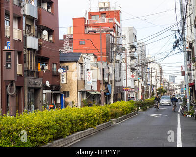 Deux cyclistes à vélo sur une rue de banlieue dans la région de Taito, à Tokyo. Banque D'Images