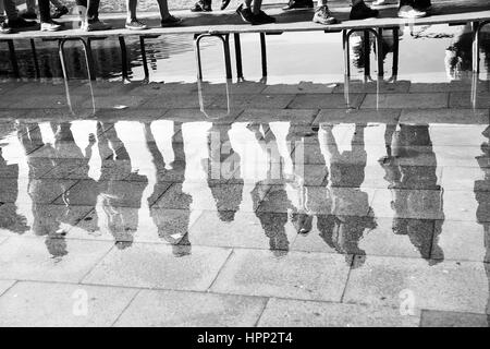 L'eau haute à Venise - les gens à pied bridge reflètent dans une énorme flaque d'eau sur la place San Marco à Venise, Italie. Image en noir et blanc Banque D'Images