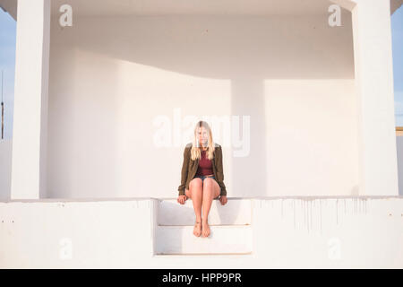 Espagne, Ténérife, portrait of young blonde woman sitting on steps Banque D'Images