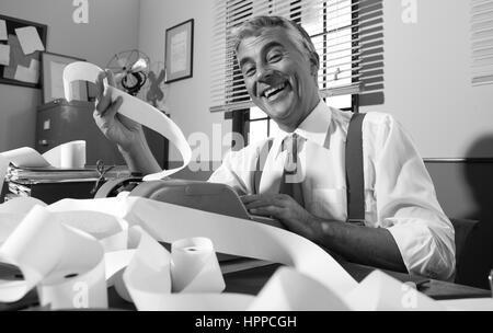 Vintage joyeux sourire comptable et travailler avec l'ajout de machine vintage années 50 bureau. Banque D'Images