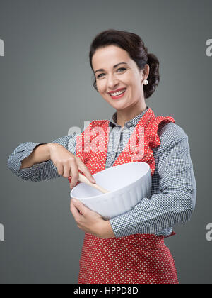 Vintage femme cuire le mélange des ingrédients dans un bol et souriant Banque D'Images