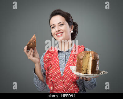 Vintage femme tablier en mangeant une tranche de panettone italien traditionnel, pâtisserie maison Banque D'Images