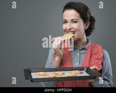 Smiling vintage femme préparant de délicieux cookies servis sur une plaque de cuisson Banque D'Images