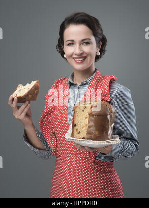 Vintage femme tablier en mangeant une tranche de panettone italien traditionnel, pâtisserie maison Banque D'Images