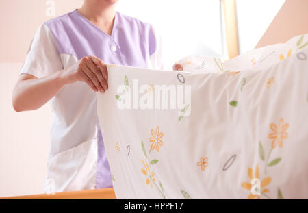 Woman making bed et changer la literie dans la chambre. Banque D'Images