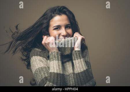 Attractive young woman with high collar sweater smiling at camera Banque D'Images