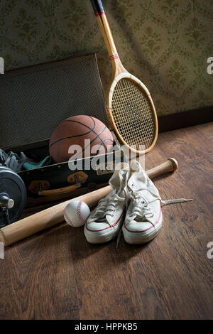 Valise vintage avec des équipements sportifs sur plancher en bois avec des chaussures de toile sur le premier plan. Banque D'Images