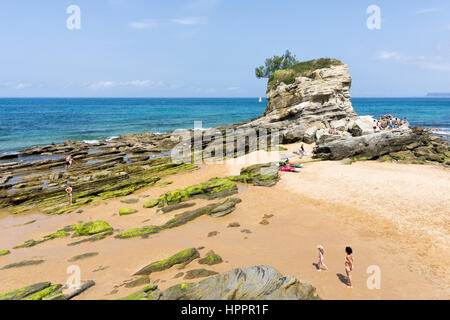 Les gens le bronzage et marcher dans une plage avec un gros rocher Banque D'Images