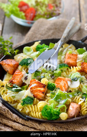 Les pâtes italiennes avec des morceaux de filet de saumon, sauce au raifort et une crème de poireau et servi dans une poêle de fer avec une salade Banque D'Images