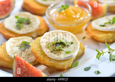 Épicé au four avec fromage de chèvre apéritifs crostini et herbes fraîches servi sur une assiette de service avec blanc fig la moutarde et figues fraîches Banque D'Images