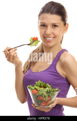 Joyful young woman eating a salad isolé sur fond blanc Banque D'Images