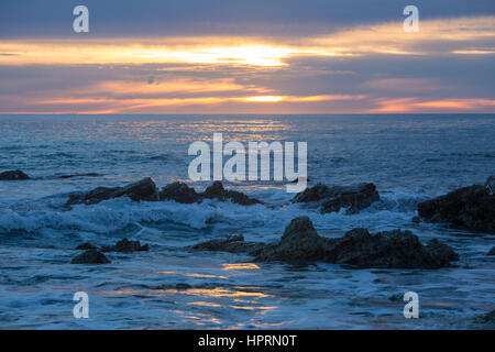 Kaikoura, Canterbury, Nouvelle-Zélande. Vue sur l'océan Pacifique à partir de la côte rocheuse au lever du soleil, lumière dorée reflétée dans l'eau. Banque D'Images