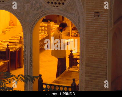 L'homme iranien barbu se lit livre autour de divans et arcades de Abbasian palace chambre à Kashan, Iran Banque D'Images