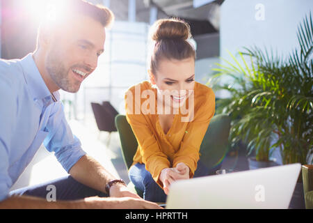 Happy young bussinesman femme était assise et travailler ensemble au bureau avec ordinateur portable et sun flare Banque D'Images