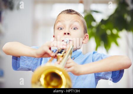 Petit garçon joue de la trompette à la maison Banque D'Images