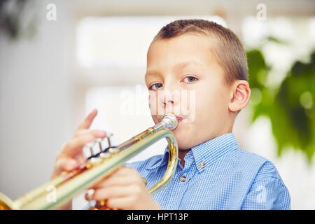 Petit garçon joue de la trompette à la maison Banque D'Images