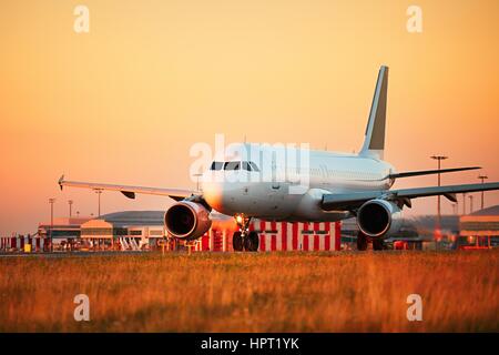 Aéroport à la lumière au coucher du soleil. Avion est le roulage vers la piste pour décoller. Banque D'Images