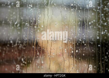 Petit garçon derrière la fenêtre sous la pluie - selective focus Banque D'Images