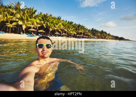 Jeune homme en vacances en tenant dans la mer. selfies Banque D'Images