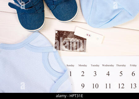 Test de grossesse avec résultat positif, l'échographie de bébé, des vêtements pour nouveau-nés et le calendrier, concept de l'extension de la famille et s'attendant pour bébé Banque D'Images
