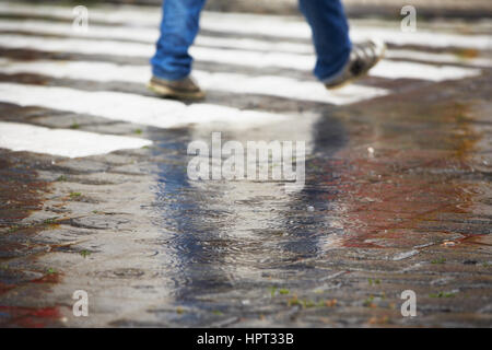L'homme marche sur le passage piétons dans la pluie - selective focus Banque D'Images