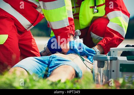 La réanimation. L'équipe de sauvetage (médecin et d'un ambulancier) ressusciter l'homme de la rue. Banque D'Images