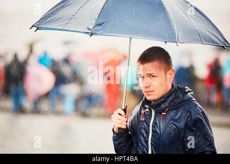 Jour de pluie. Jeune homme est tenue bleu et marcher dans la pluie. Rue de Prague, République tchèque. Banque D'Images