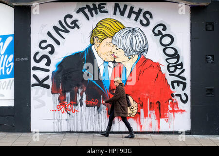 Bristol, Royaume-Uni. Feb 24, 2017. Une femme est photographié devant un nouveau morceau de street art avertissement au sujet de la mort de la NHS. Le travail d'art,une partie de 'Save the NHS' protester contre la diminution du financement accordé à l'ENM est apparu au cours des derniers jours à la Stokes Croft de la ville.La peinture montre le premier ministre et le Président peut l'emporter sur les baisers et les avertit qu'un lien trop étroit entre les deux pays après Brexit pourrait annoncer la fin de la NHS. Credit : lynchpics/Alamy Live News Banque D'Images