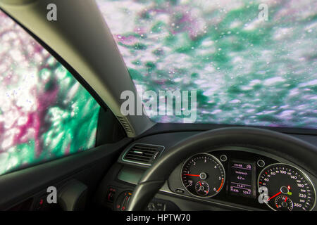 Voiture dans une station de lavage automatique, le nettoyage du site est pulvérisé sur la mousse, Banque D'Images