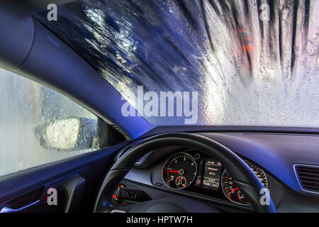 Voiture dans une station de lavage automatique, le nettoyage du site est pulvérisé sur la mousse, la rotation de la brosse de nettoyage, Banque D'Images