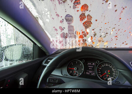 Voiture dans une station de lavage automatique, le nettoyage du site est pulvérisé sur la mousse, Banque D'Images