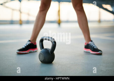 Femme libre de jambes avec un kettlebell sur un plancher de béton de garage de stationnement Banque D'Images